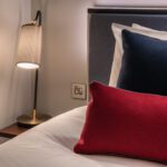 A bedside lamp, and bed with colourful pillows, located in Covent Garden.