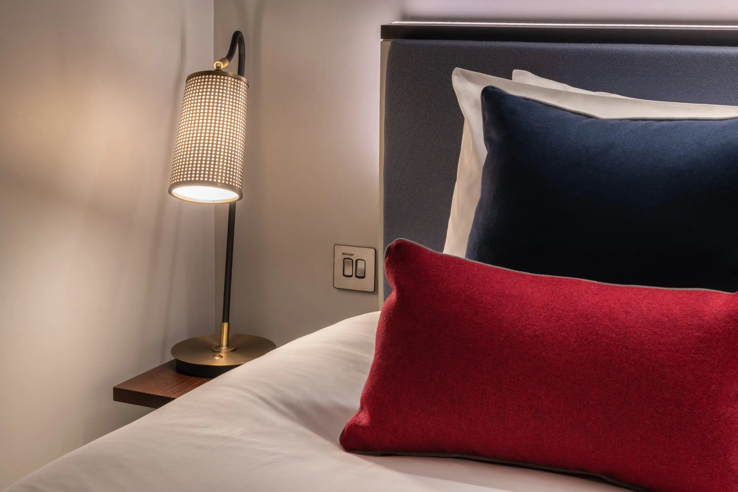 A bedside lamp, and bed with colourful pillows, located in Covent Garden.