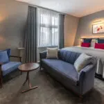 A junior suite with a double bed, a small dining area and a sofa, located in Covent Garden.