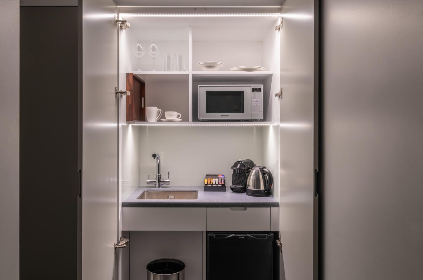 A miniature kitchen, with a built in fridge and microwave.