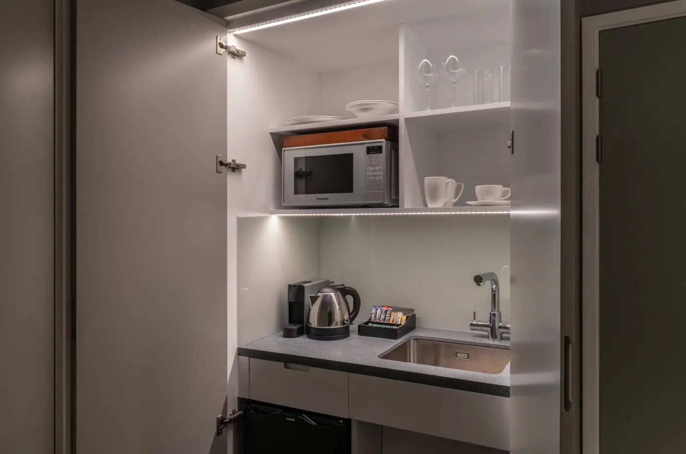 A miniature kitchen with a built in fridge and microwave, located in Covent Garden.