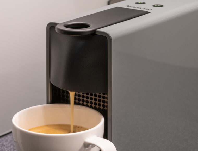 A coffee machine, pouring coffee into a mug.