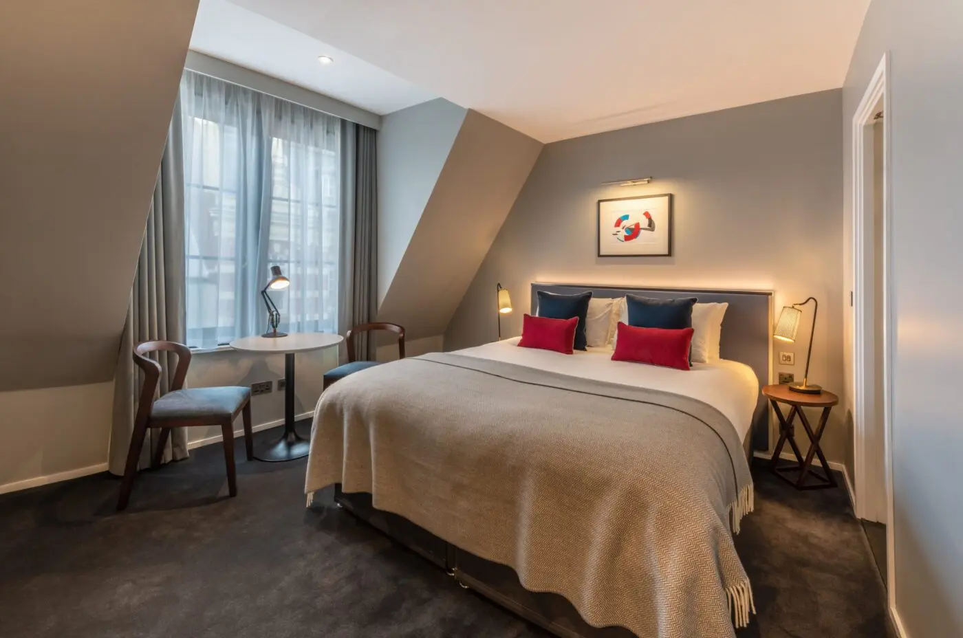 A spacious superior room with a double bed, and dining table, located in Covent Garden.