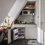 A miniture suite kitchen, with a small table, fridge and microwave.