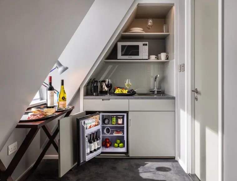 A miniture suite kitchen, with a small table, fridge and microwave.