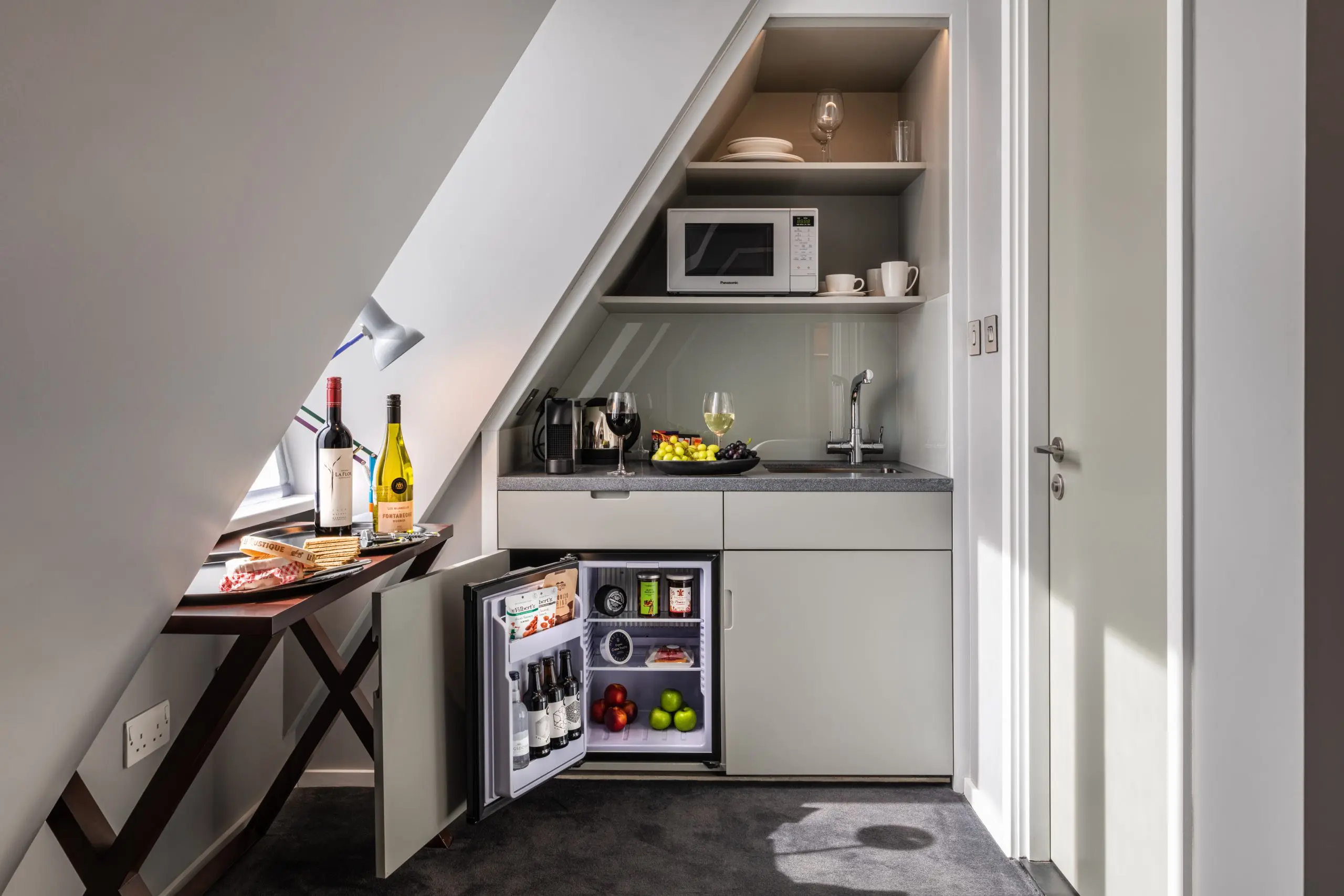 A miniture suite kitchen, with a small table, fridge and microwave.