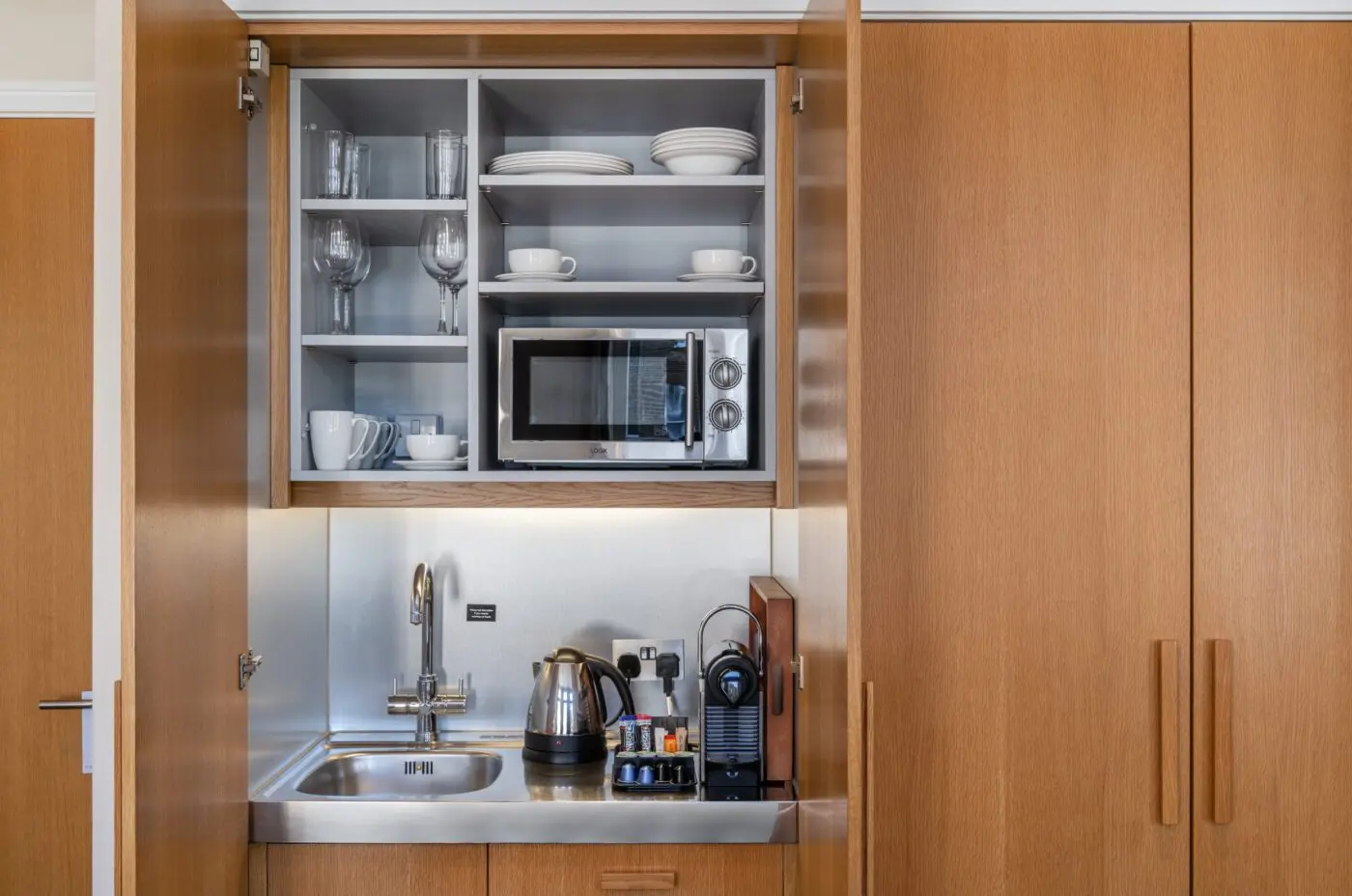 A miniature kitchen, with a built in fridge and microwave, located in Kensington.