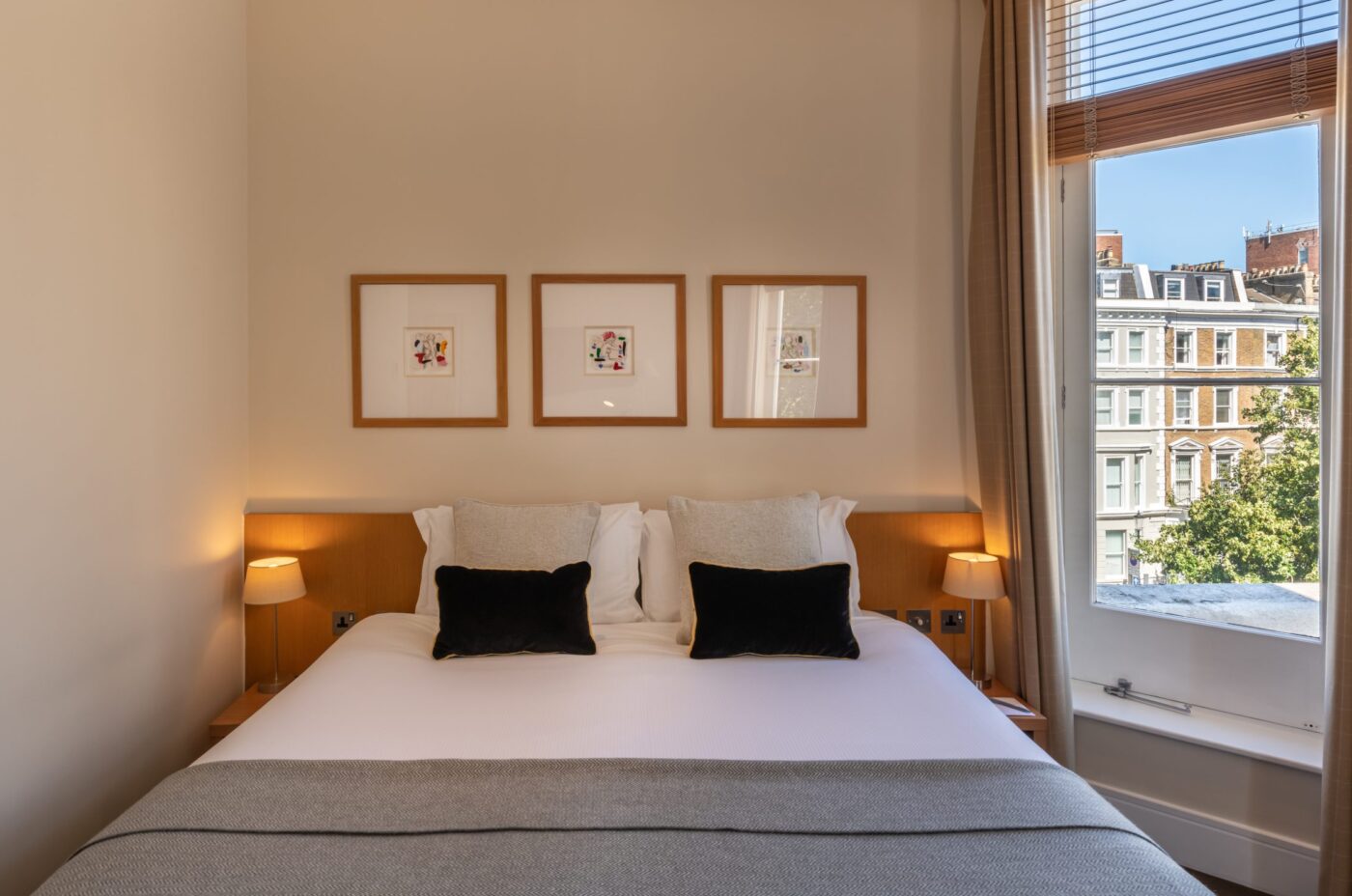 A deluxe room, with a double bed and bedside tables, located in Kensington.