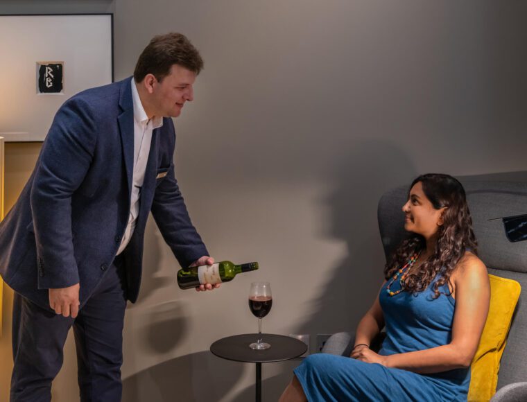 A Resident team member pouring a glass of red wine for a guest.