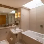 A superior bathroom with a large built in mirror and bathtub, located in Kensington.