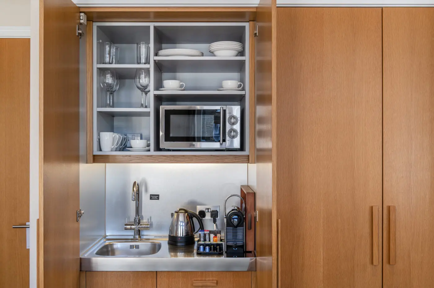 A miniature kitchen, with a built in fridge and microwave.