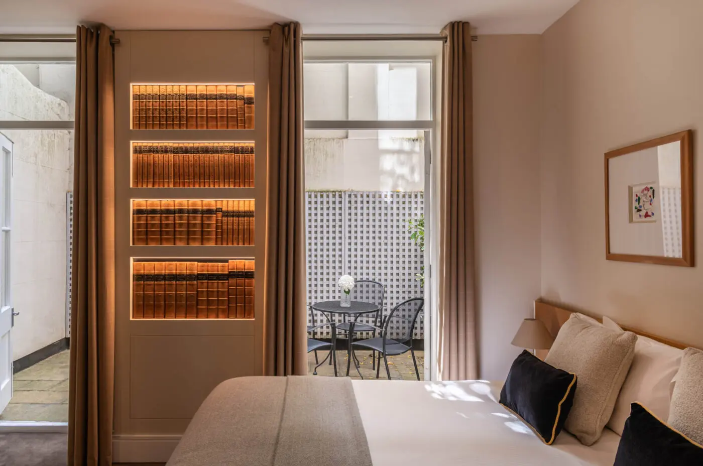 A deluxe room with a double bed, built in shelves and a patio located in Kensington.