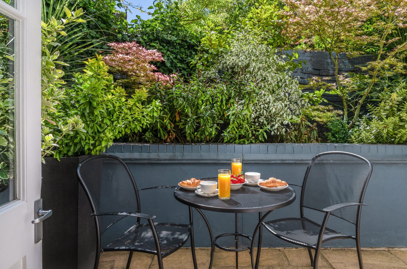 A patio with two dining chairs and breakfast.