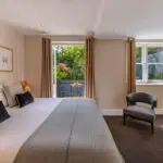 A large bedroom with a television, desk and balcony.