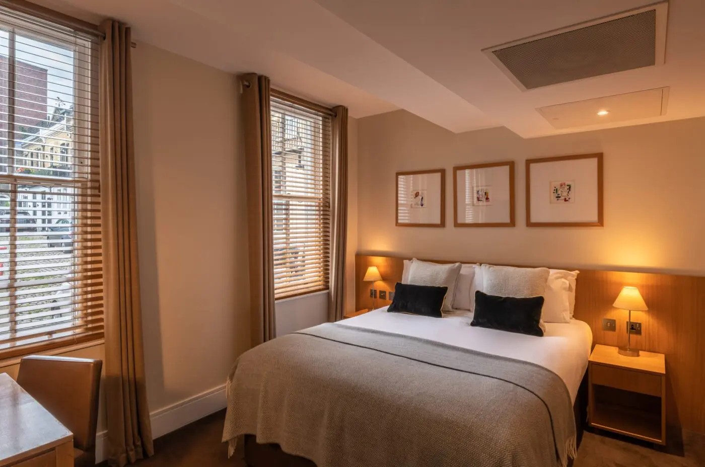 A large bedroom, with a double bed, bedside tables and desk, located in Kensington.