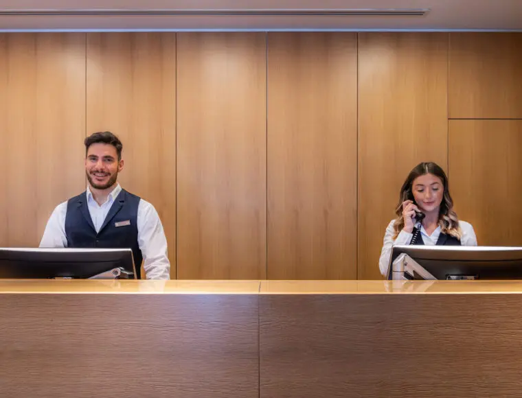 Two hotel professionals working in the reception area.