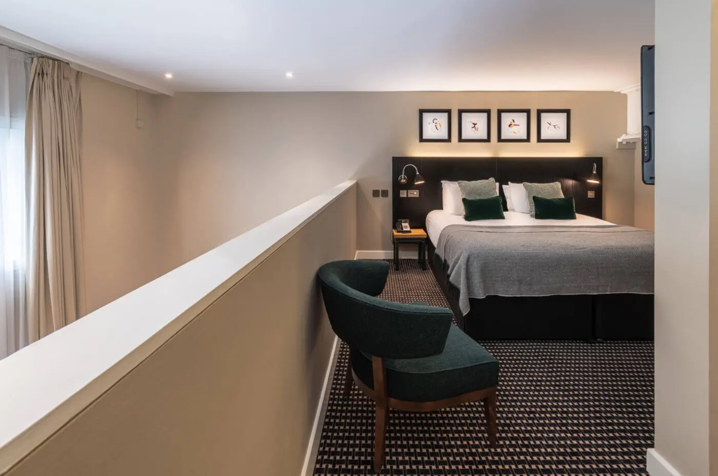 A suite with a double bed, arm chair and bedside table.