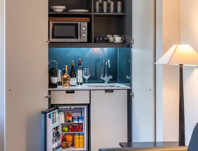A miniature kitchen with a built-in fridge and microwave.