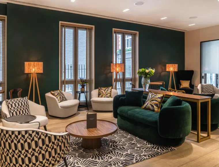 A hotel lounge with sofas, a coffee table and lamps.