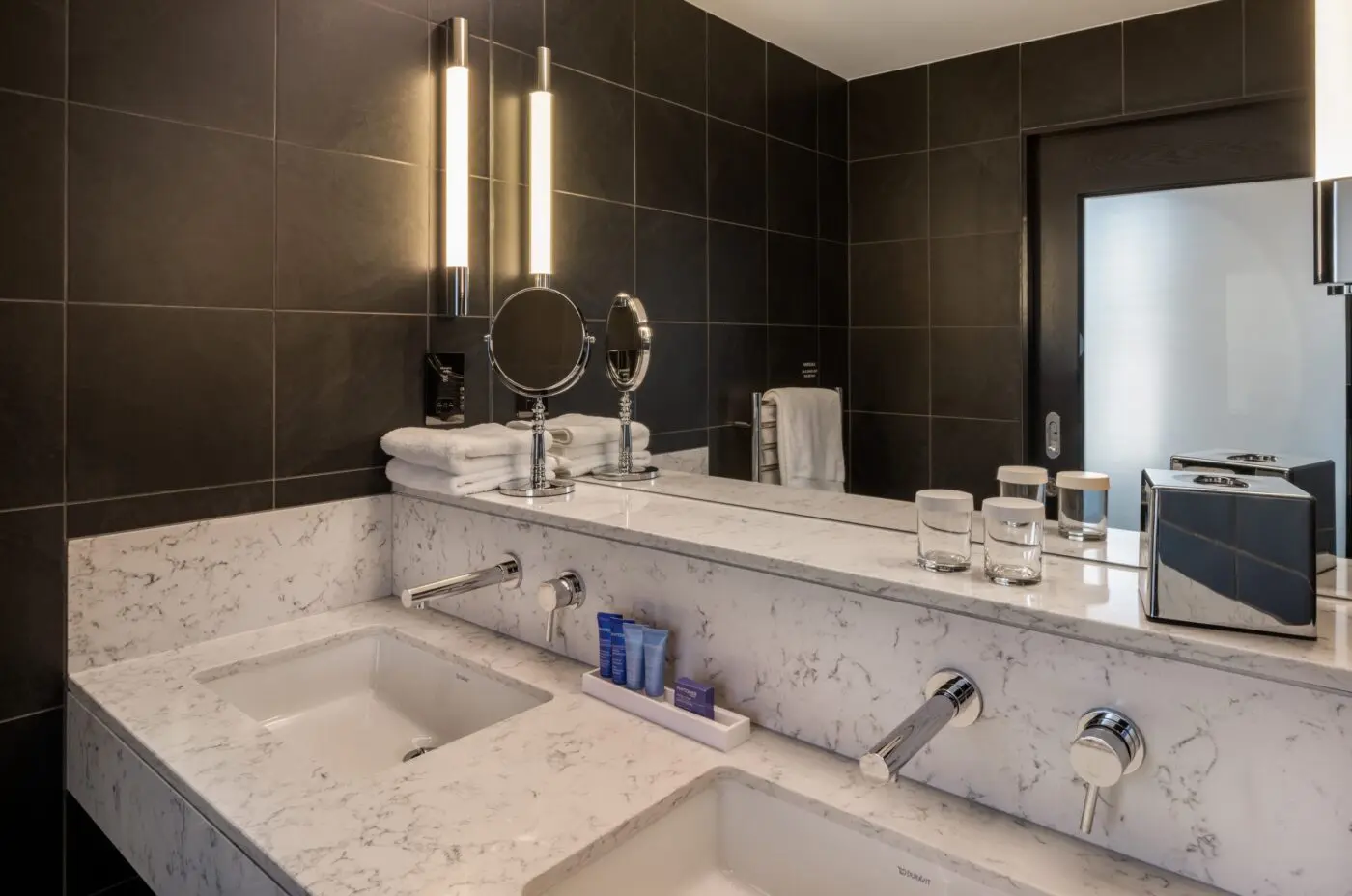 Bathroom counter with two sinks and kitchen amenities.