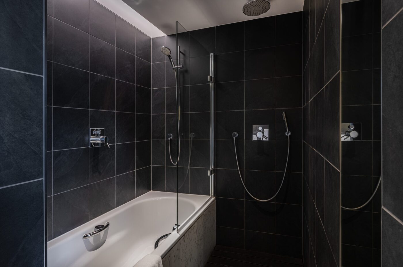 Spacious bathroom with a built in bathtub and shower, with an additional shower head.