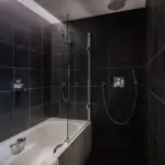 Spacious bathroom with a built in bathtub and shower, with an additional shower head.