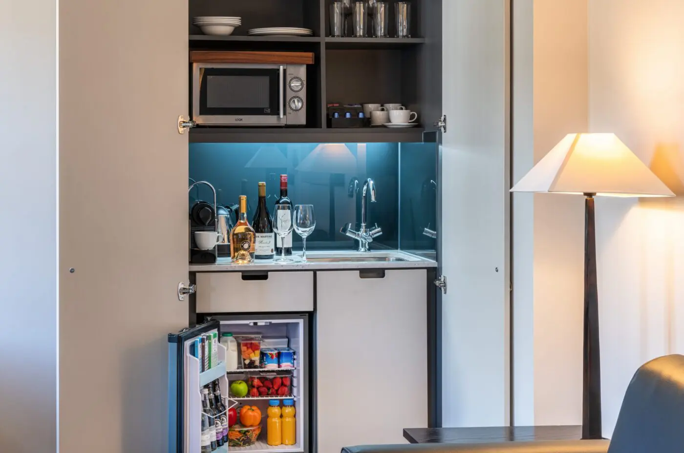 A built in miniature kitchen area with a fridge and microwave, located in Soho.