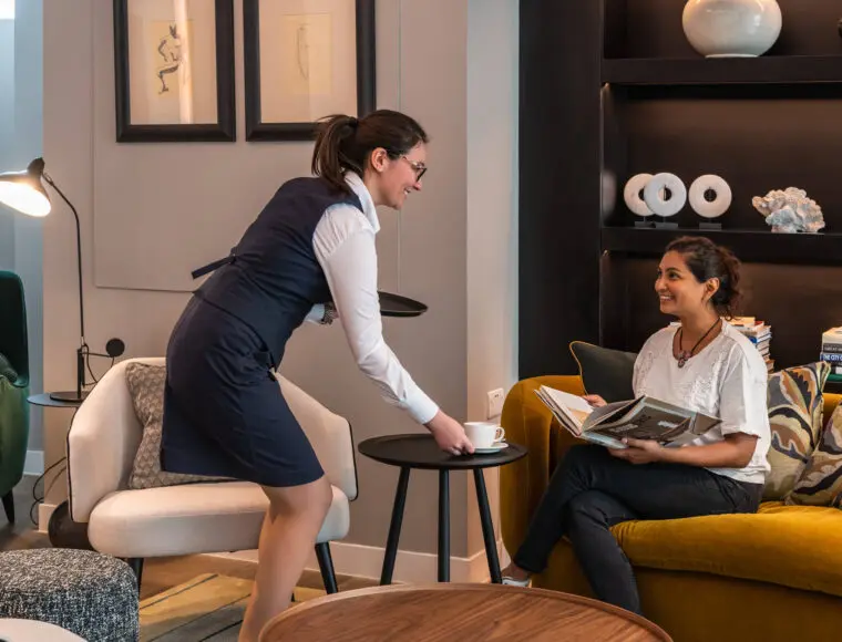 Hotel Professional providing a customer with a hot beverage.