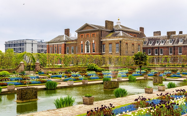 Kensington Palace in London, a large building facing plants and ponds.