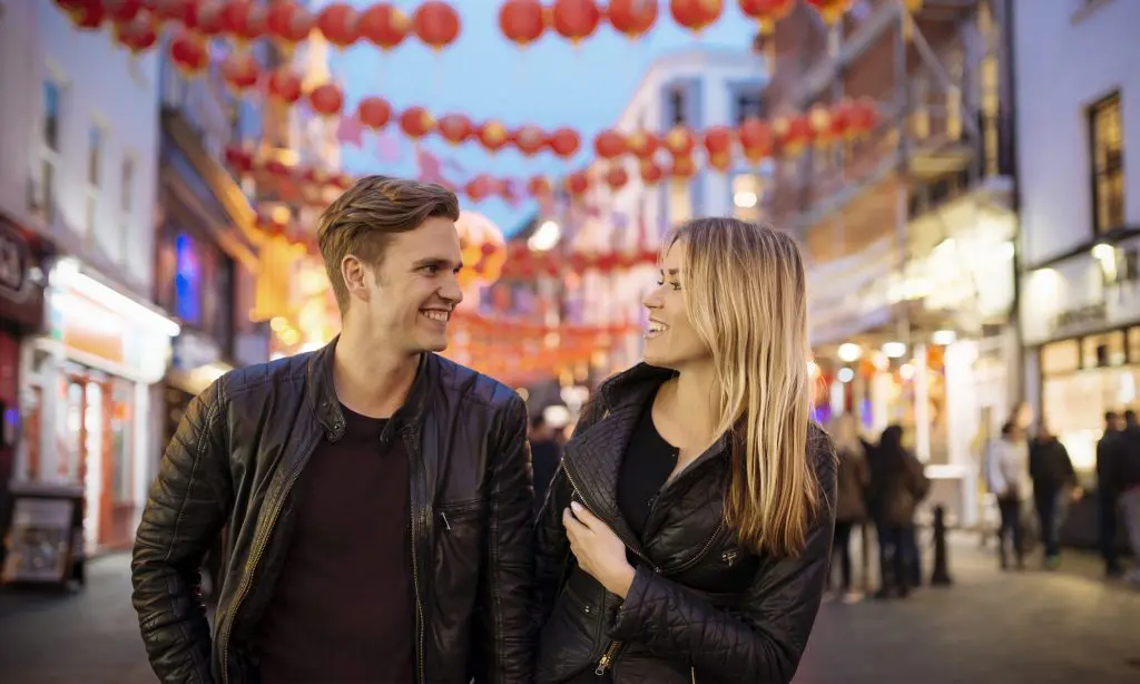 A couple smiling whilst walking through Soho.