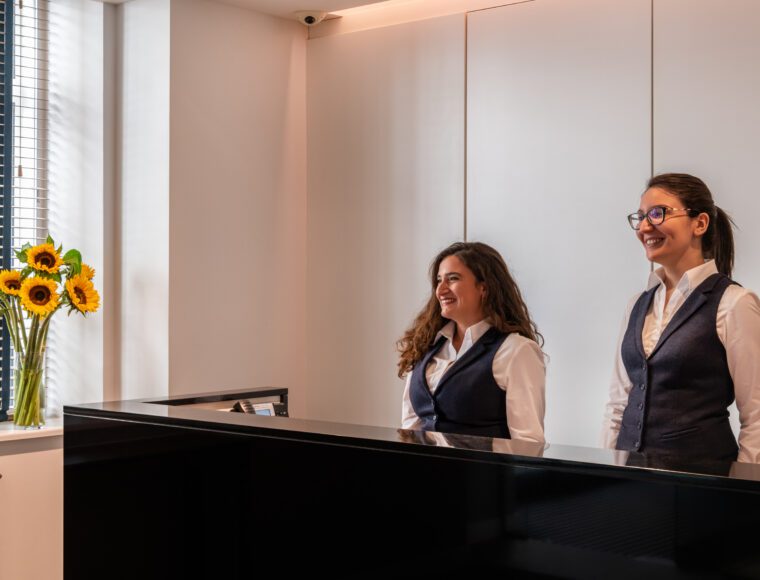 Receptionists smiling at the Reception desk of The Resident