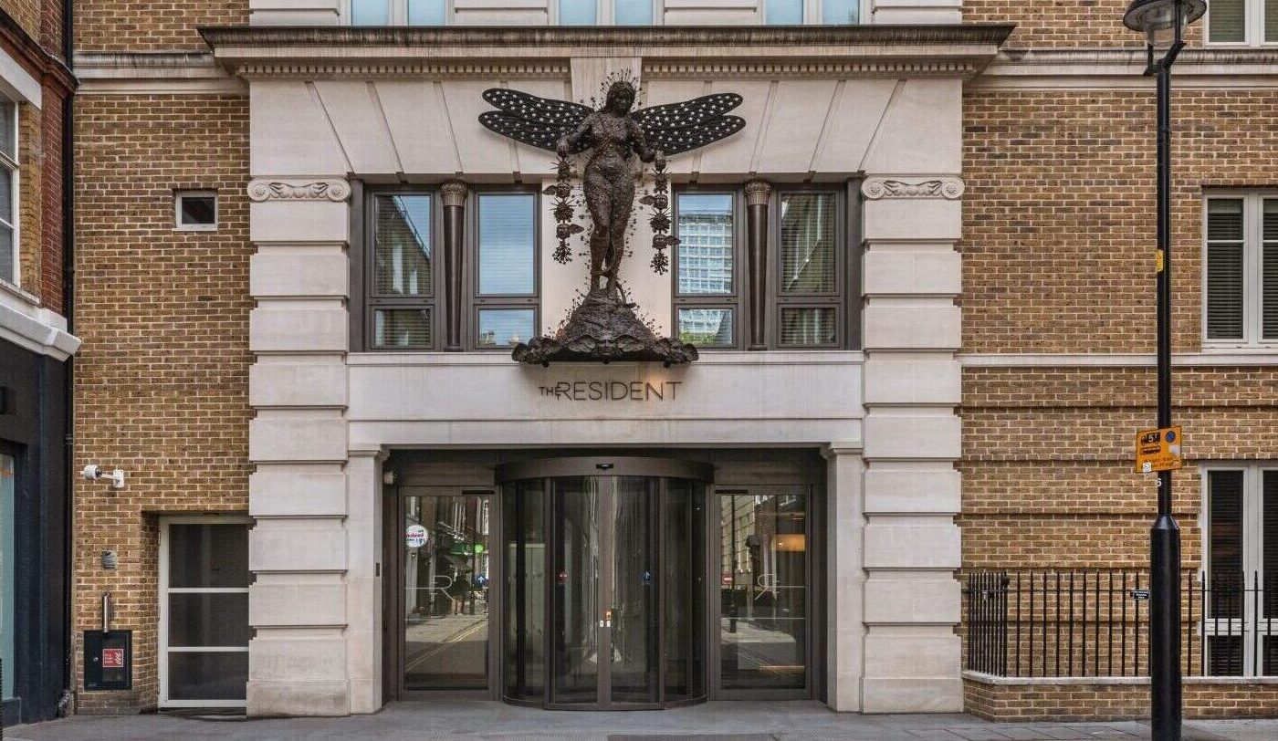 The entrance to a brick building with a large butterfly sculpture above the door and the word 